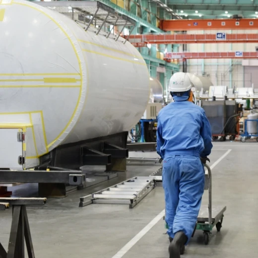 工場で大型タンクを運搬する作業員