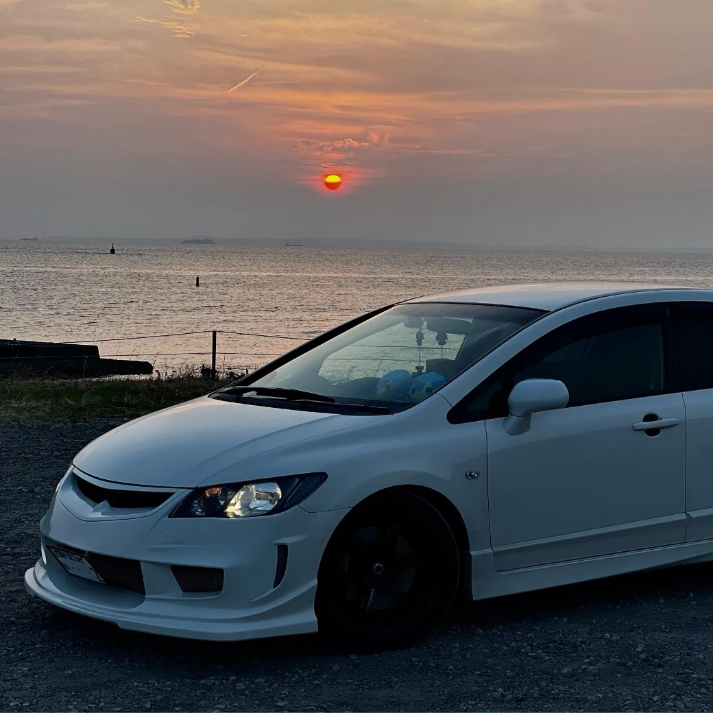 白いスポーツカーと夕日の海岸の風景