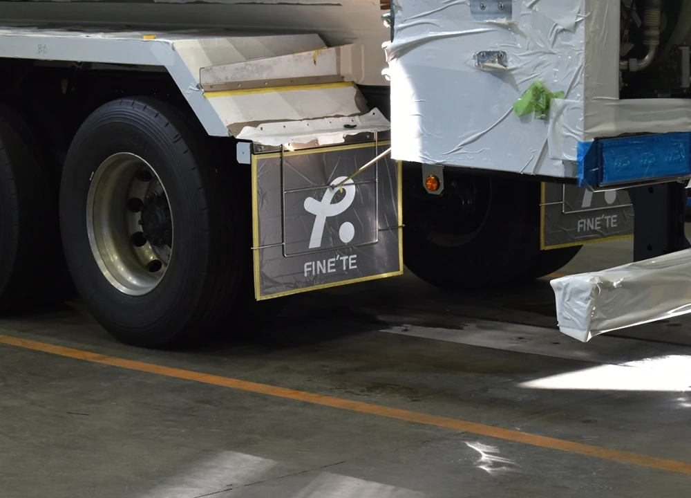 納車前の大型タンクローリーの泥除け部分。FINE'TEのロゴが入った保護シートで養生されている様子	