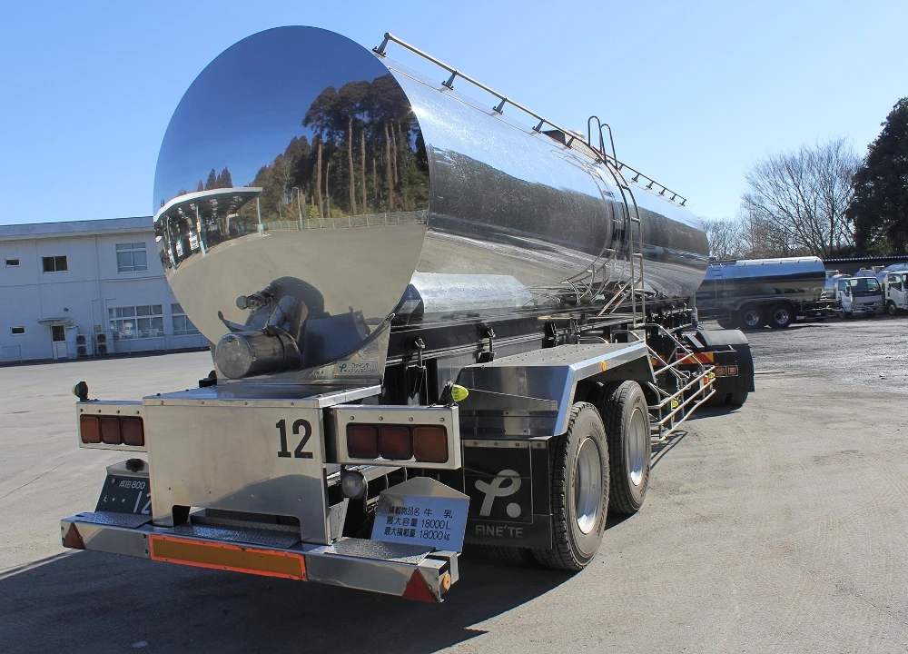 青空の下に停車する、鏡面仕上げが美しい大型ミルクタンクローリーの後方からの全景