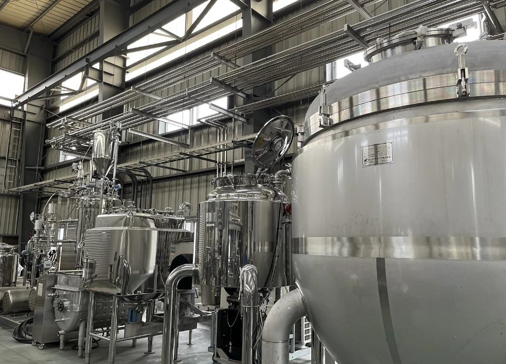 食品や薬品用と思われる、大型のステンレス製攪拌タンクや製造設備が並ぶ清潔な工場の内部