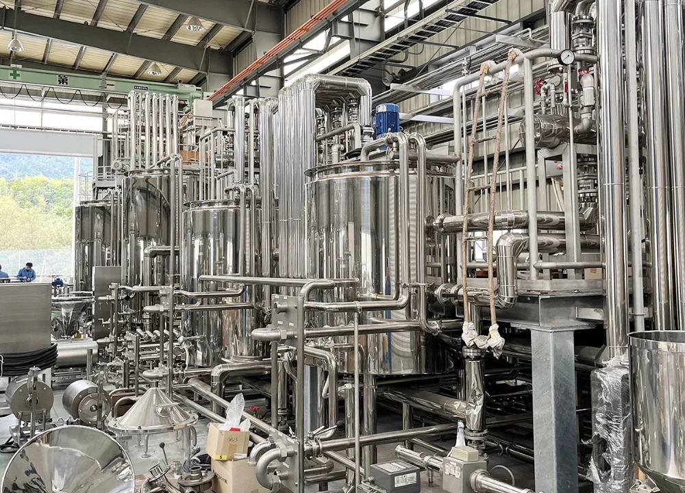 工場内に設置された、複雑かつ精密に組み上げられた大型ステンレス製サニタリー配管システムとタンク群