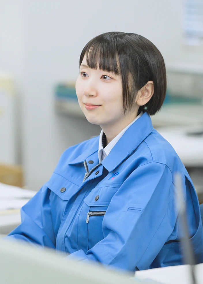 青いジャケットを着た女性がデスクに座っている様子