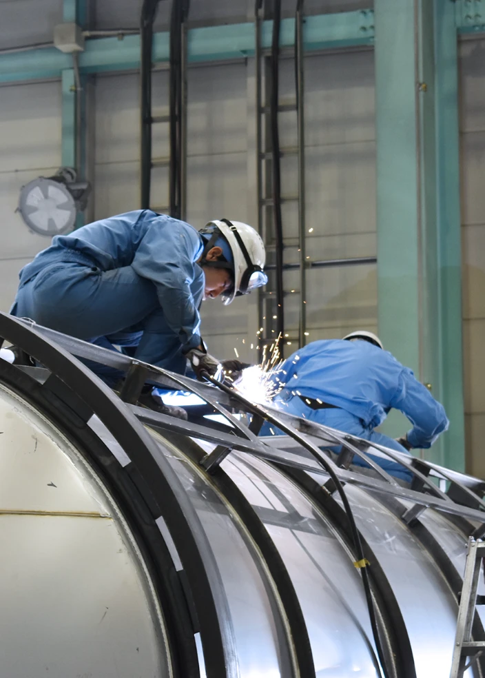 大きな金属構造物で作業する労働者が溶接している様子