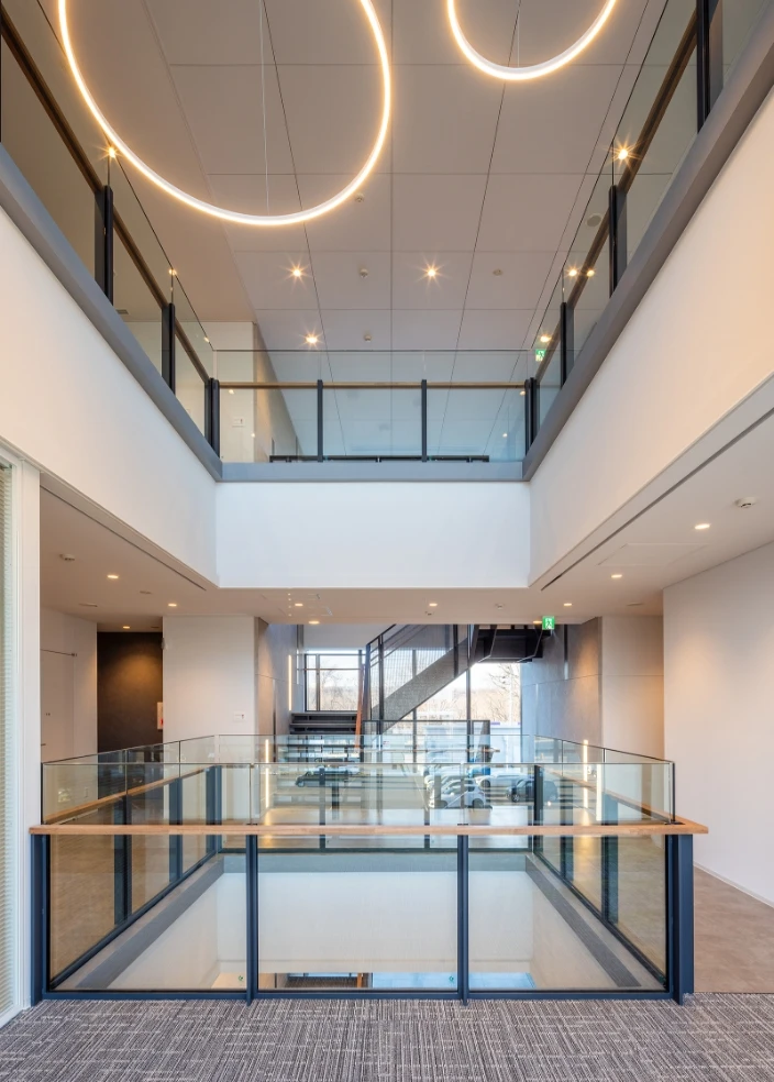 吹き抜け構造の明るいオフィス内観とガラス手すりの廊下