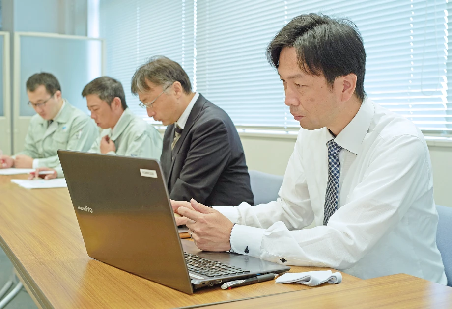 会議室のデスクでノートパソコンを使い打ち合わせをする社員