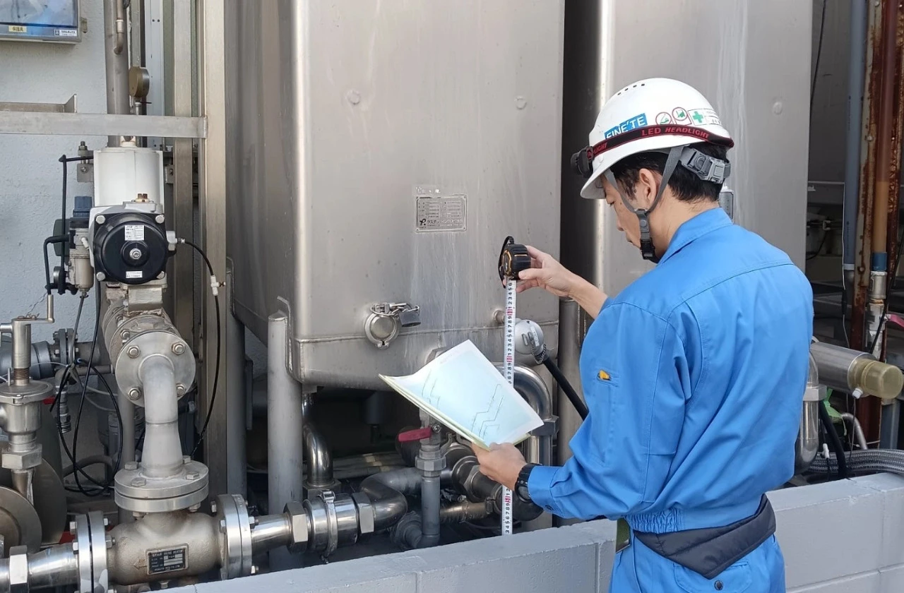 工場の配管設備を点検する作業員の写真