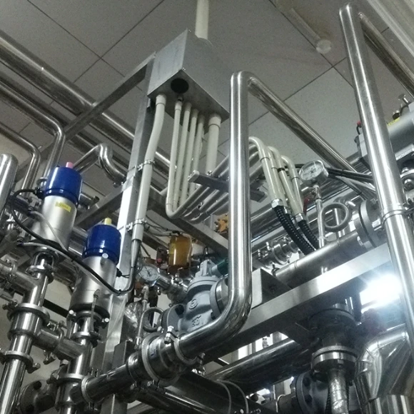 工場のステンレス配管とバルブシステムの内部設備写真。
