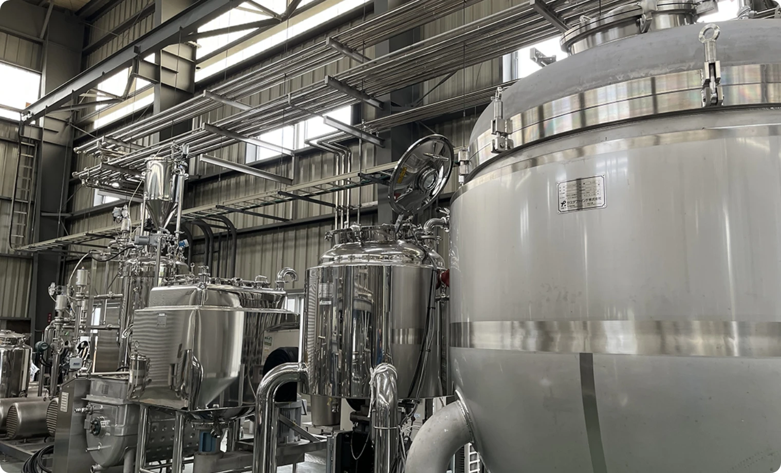 工場のステンレス製タンクと配管設備の内部写真