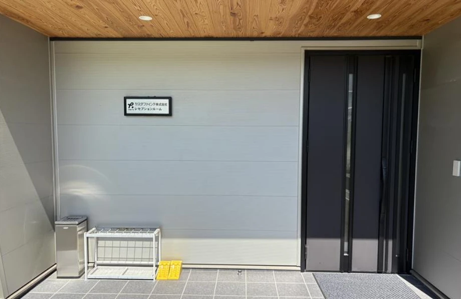 モダンな住宅の玄関、黒いドアと灰色の壁、木製天井の外観。