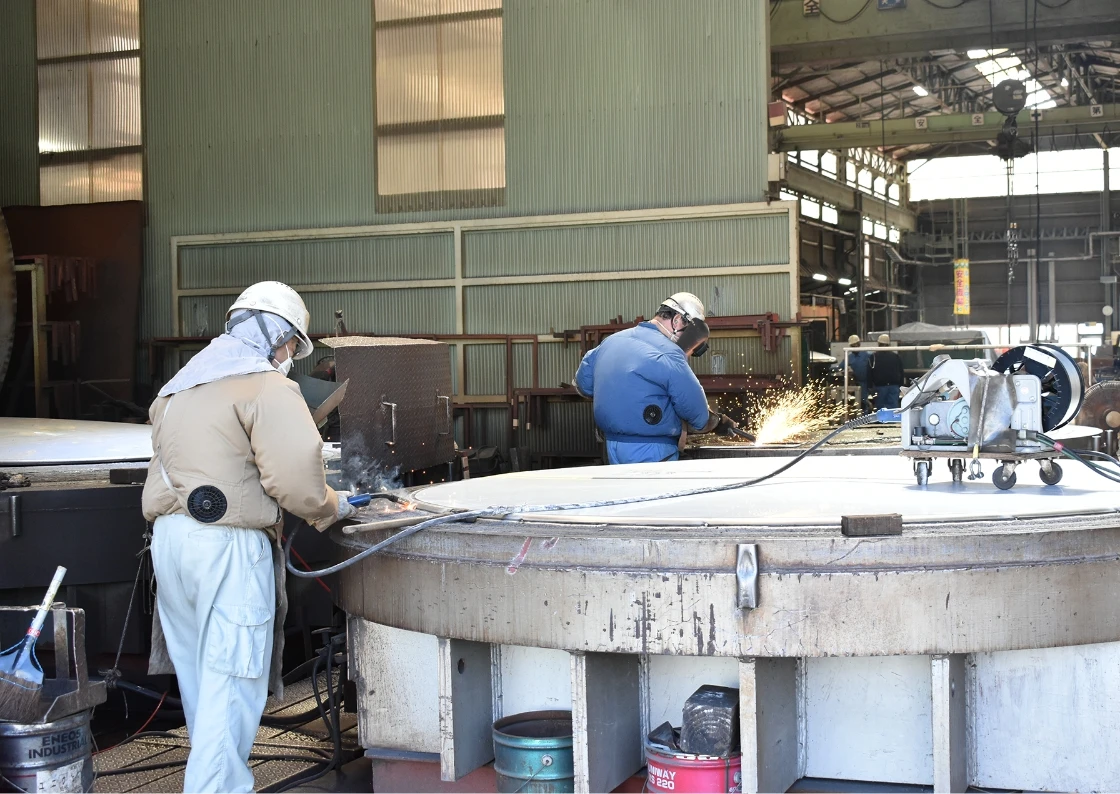 工場で作業員が溶接作業を行っている光景