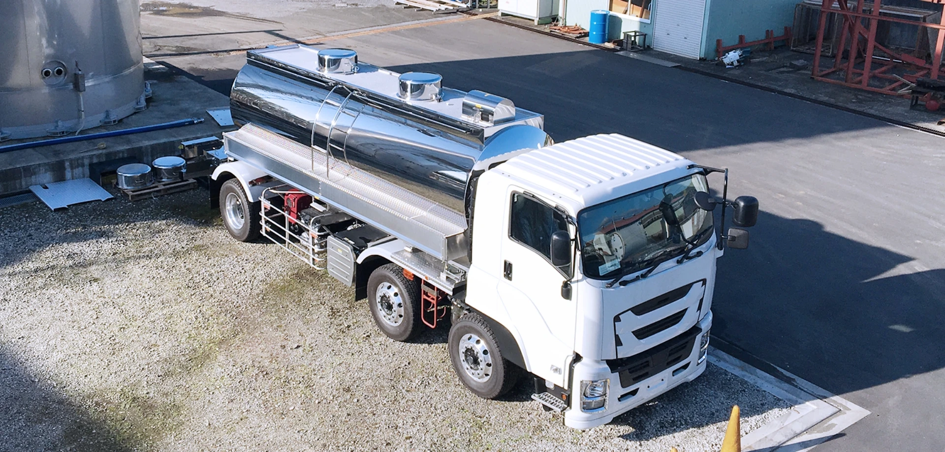 ステンレス製タンク付き白色の大型ミキサー車の駐車場風景