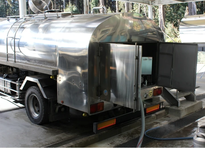 ステンレス製のタンクを備えた乳製品配送用トラック、充填ホース接続中