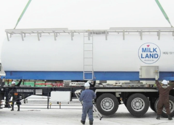 ミルクランドの牛乳タンクコンテナを運ぶ作業員とトラック。