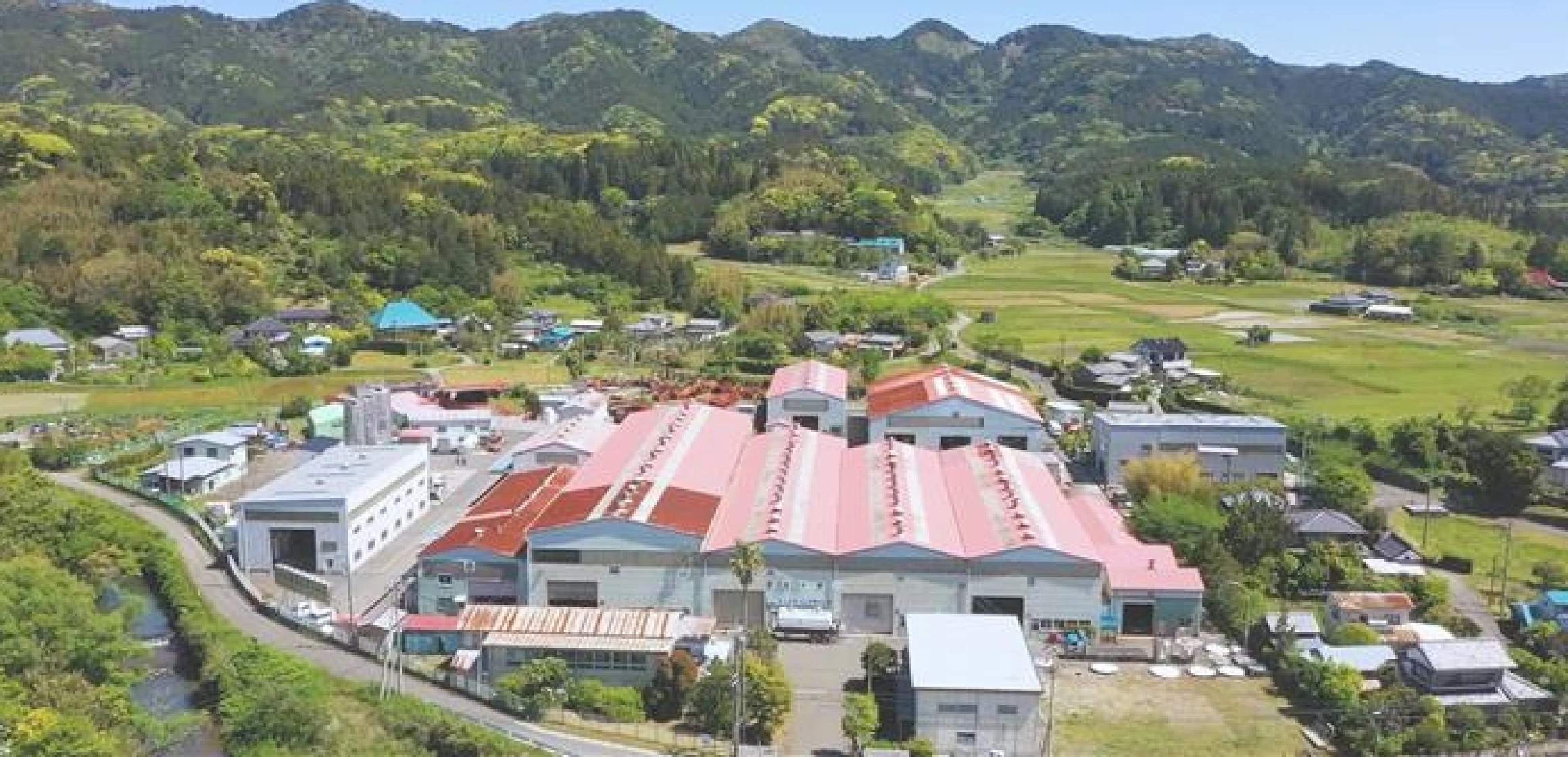 田舎の緑豊かな山々に囲まれた工場の航空。